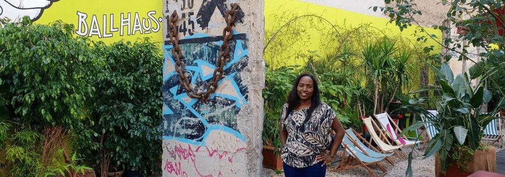 Dr Maina standing next to a segment of the Berlin Wall